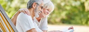 An elderly couple comfortably seated in a chair, reading a book together, enjoying a peaceful and intimate moment.